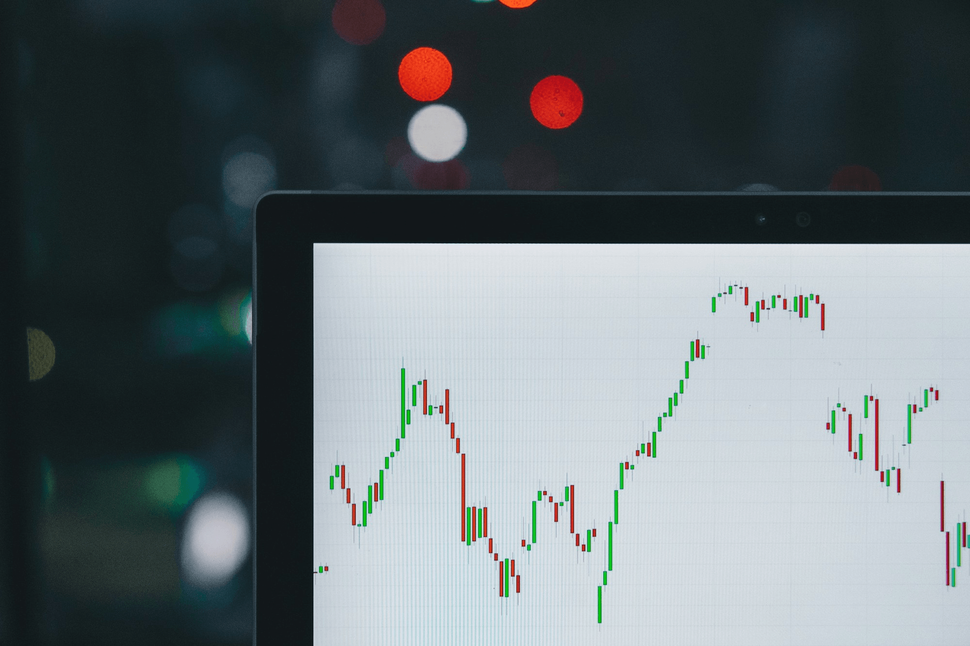 Tela com gráfico de candlestick do mercado financeiro, em ambiente escuro.